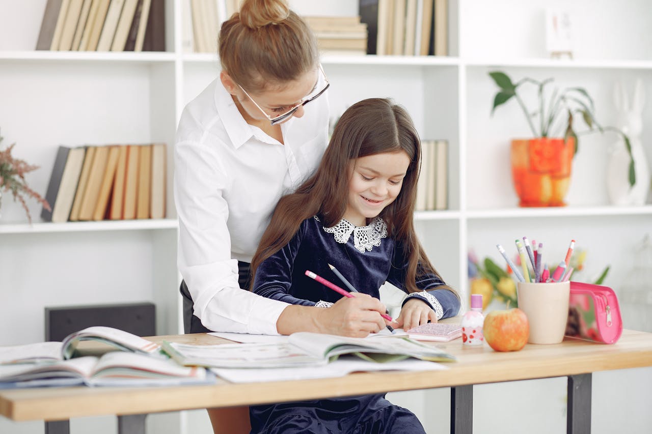 A teacher guides a young girl in a classroom setting, promoting learning and focus.